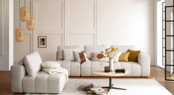 Gemütliches Wohnzimmer mit beiger Couch, Korb-Lampen und einem runden Tisch. Perfekt für slow living einrichtung.