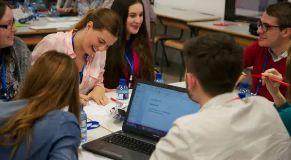Jóvenes participan en actividades para trabajar la asertividad en el aula, colaborando en un proyecto.
