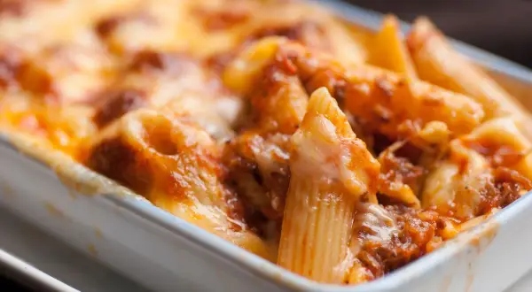Un invitante piatto di pasta al forno, con penne ricoperte da un ricco sugo e formaggio fuso dorato.