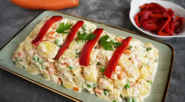 Spanischer Kartoffelsalat mit Thunfisch und Mayonnaise, garniert mit Paprika und Petersilie. Ein köstlicher Genuss!