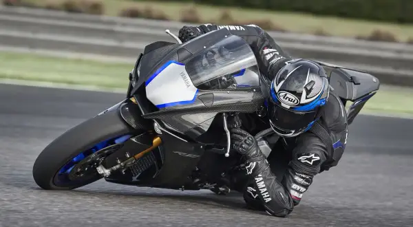 Piloto en Yamaha R1, la moto más potente, inclinado en una curva en circuito.