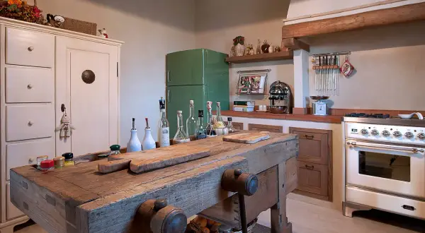 Un vecchio banco da falegname diventa un'isola cucina rustica, con taglieri e bottiglie d'olio.