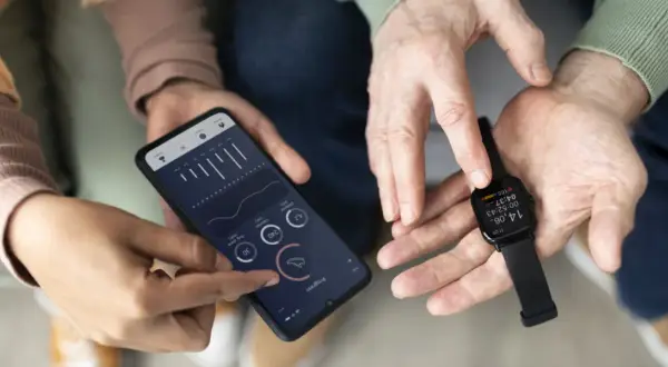 Dwie osoby analizują dane z zegarka Amazfit na smartfonie. Amazfit to firma znana z inteligentnych urządzeń do śledzenia aktywności.