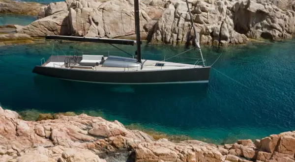 Un elegante yacht Brenta naviga in acque cristalline, ormeggiato tra scogliere rocciose.