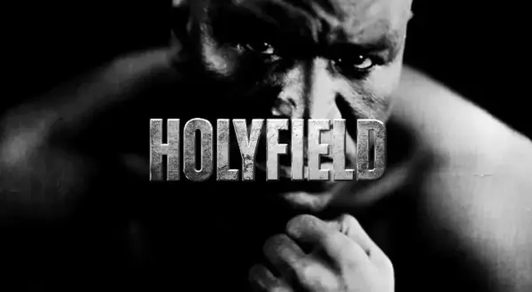 A close-up, black and white portrait of Evander Holyfield, the legendary boxer, with the word "HOLYFIELD" emblazoned across his face.