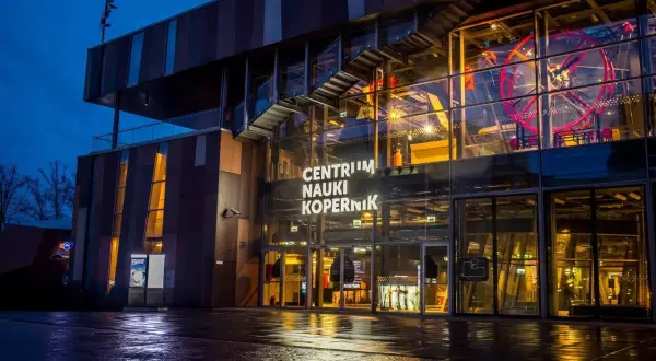 Centrum Nauki Kopernik nocą, z widocznym wejściem i fragmentem ekspozycji.