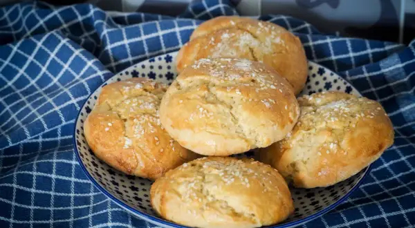 Petits pains à burger dorés et moelleux, saupoudrés de graines de sésame, dans une assiette décorée.
