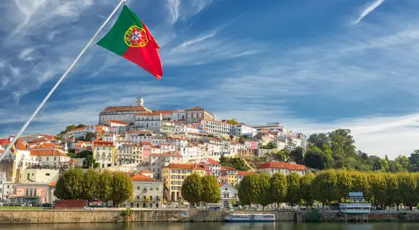 Flaga Portugalii nad rzeką. Miasto na wzgórzu, idealne na wakacje, gdzie portugalia temperatura wody zachęca do kąpieli.