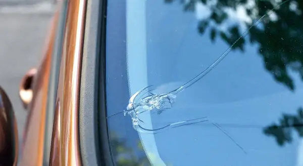 En spricka i vindrutan på en orange bil. Det ser ut som att det är dags att laga stenskottet innan det blir värre.