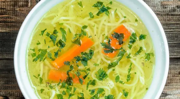 Aromaticzny rosół z makaronem, marchewką i natką pietruszki. Czy rosół ma białko? Tak, dzięki mięsu, z którego jest gotowany, dostarcza cennego białka.