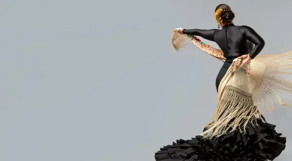 Bailarina con traje de flamenca negro y mantón bordado. Un ejemplo de cómo planchar un traje de flamenca para que luzca impecable.
