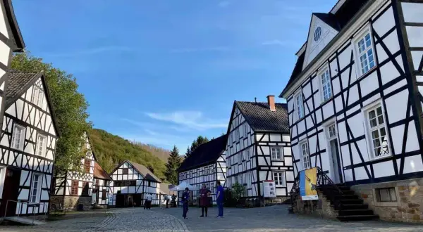 Fachwerkhäuser in einem Freilichtmuseum, das zeigt, was ist ein Freilichtmuseum. Besucher schlendern über Kopfsteinpflaster.