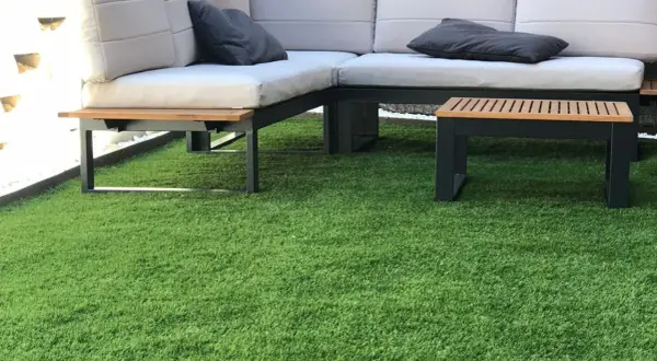 Sofá moderno y mesa auxiliar sobre césped artificial. ¿Cuánto cuesta poner césped natural?