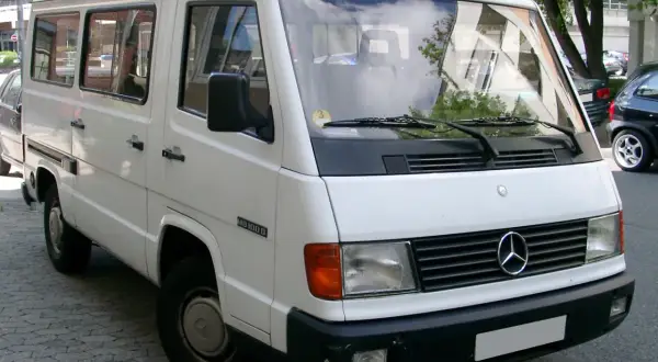 Biały Mercedes MB 100 D zaparkowany na ulicy. Klasyczny van z lat 90.