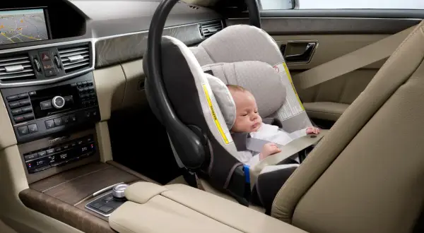 Un bébé dort paisiblement dans un siège auto, prêt pour le voyage. La **taille pour monter devant en voiture** est parfaite pour ce siège.