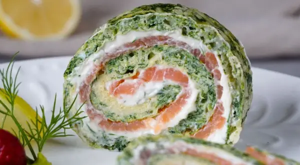 Ein saftiger Spinat Lachs Rolle auf einem Teller, garniert mit Dill und Zitrone.