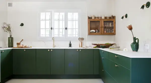 Cuisine moderne avec des armoires vert forêt profond. La couleur mur cuisine est blanc cassé, contrastant avec les meubles sombres.