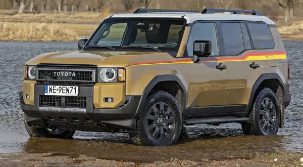 Złoty Toyota Land Cruiser wjeżdża do wody, gotowy na przygodę.