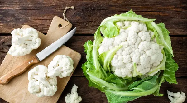 Świeży kalafior na drewnianym blacie. Zastanawiasz się, ile kalorii ma kalafior? To niskokaloryczne warzywo idealne na zdrową dietę.
