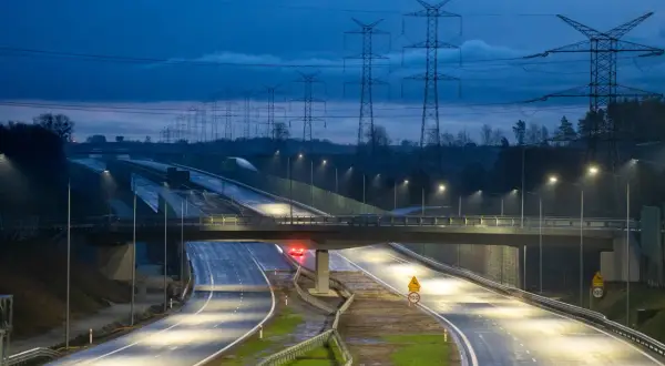 Nowa obwodnica Żukowa nocą, oświetlona latarniami, z linią wysokiego napięcia w tle.