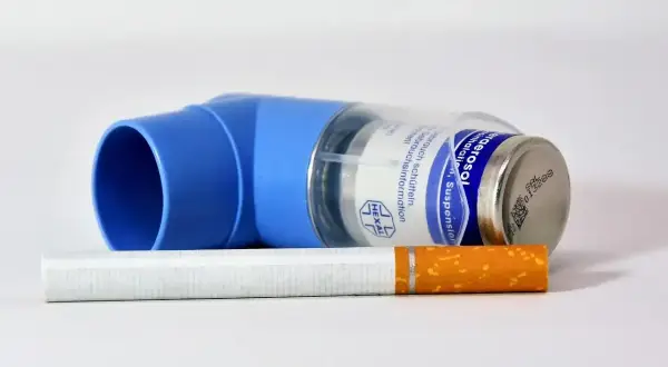 Niebieski inhalator leżący na papierosie.