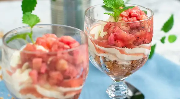 Två glas med en härlig dessert av rabarber i glas, varvad med krämig vanilj och smulad kaka. En frisk och somrig smakupplevelse.