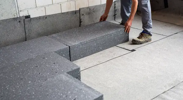 Układanie płyt styropianowych pod ogrzewanie podłogowe. Kluczowa jest minimalna grubość styropianu dla efektywnego rozprowadzania ciepła.