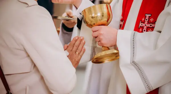 Kapłan podaje kielich podczas komunii. Czy po spowiedzi trzeba przyjąć komunię? To ważny moment duchowy.