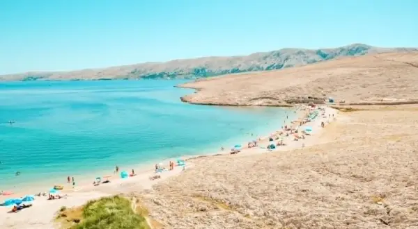 Turkusowe jakie morze jest w Chorwacji? Piękna plaża z ludźmi, parasolami i górami w tle.