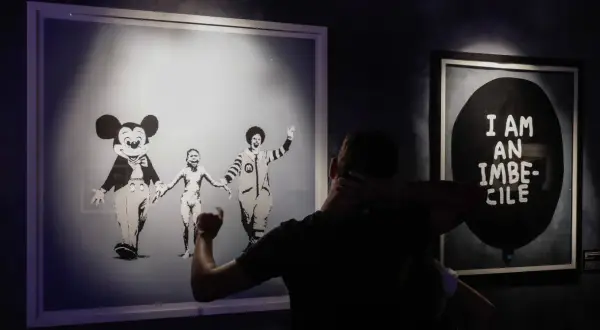 Wystawa "Banksy zdemaskowany" prezentuje dzieła artysty, w tym obraz z postaciami Myszki Miki i Ronalda McDonalda trzymających się za ręce.
