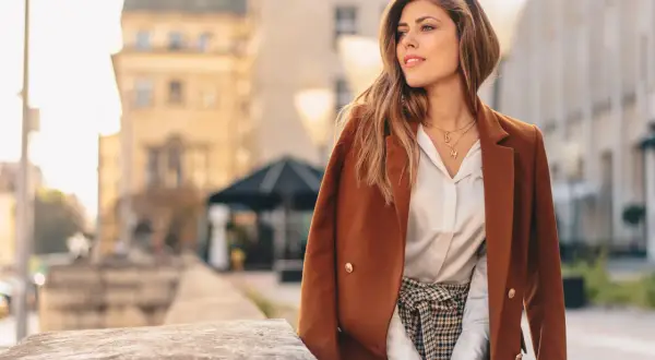 Elegancka kobieta w brązowej marynarce i białej koszuli, w stylizacji z nutą sepia kolor.