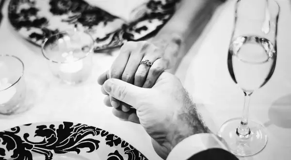 Mani intrecciate, un anello che simboleggia 40 anni di matrimonio smeraldo o rubino. Brindisi con champagne per celebrare un amore duraturo.