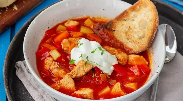 En värmande kyckling soppa med paprika, potatis och en klick gräddfil. Serveras med rostat bröd.