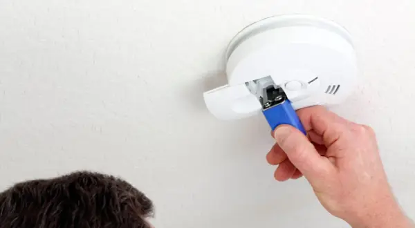 Ein Mann wechselt die Batterie des Rauchmelders, da diese leer ist.