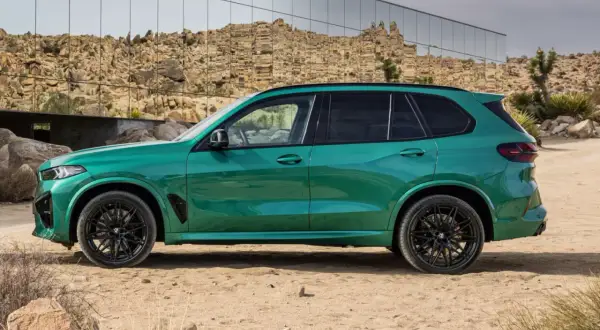 Zielony SUV, idealne ekonomiczne auto na długie trasy, zaparkowany na pustynnym tle z nowoczesnym budynkiem w tle.