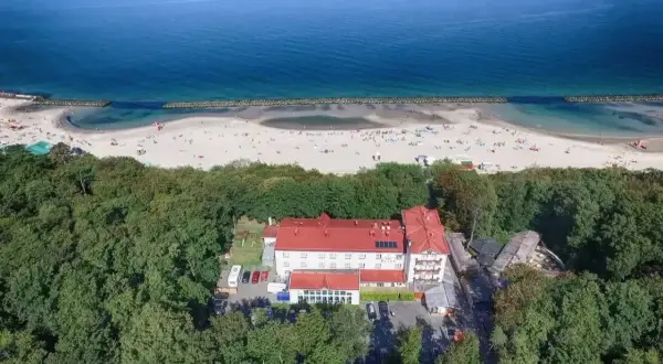 Widok z lotu ptaka na resort spa plaza otoczony lasem, z plażą i morzem w tle.