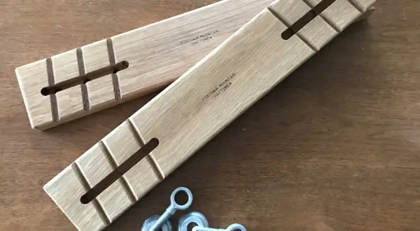 Two wooden batter boards with slots and notches, alongside eye bolts and nuts, ready for a construction project.