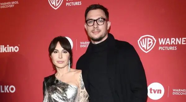 Blanka Lipińska z partnerem na czerwonym tle z logo Warner Bros. Pictures.