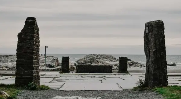 Kamienne filary i kamienna ława na placu przy morzu, jakby na **verdens ende**.