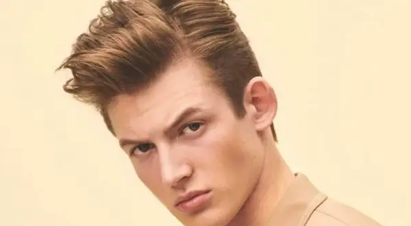 Un jeune homme arbore une coupe de cheveux homme mi long dégradé, avec du volume sur le dessus et des côtés plus courts.