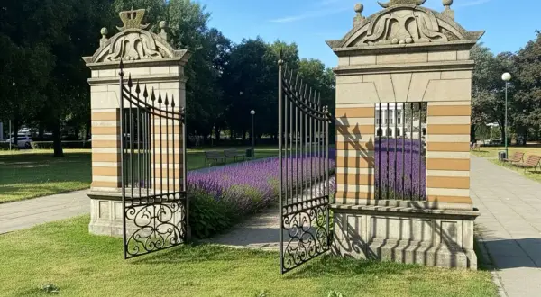 Otwarta brama w parku, z kwitnącą lawendą i ławkami w tle.