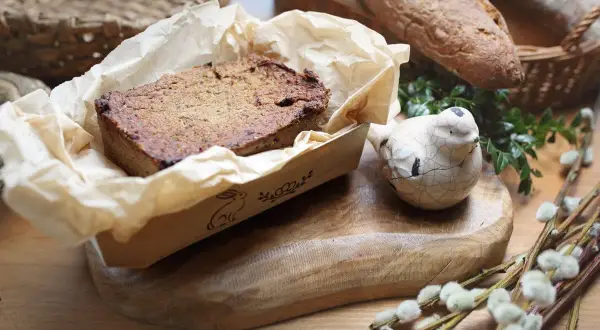 Pyszny pasztet z królika w papierowej foremce z zajączkiem, obok ceramiczny ptaszek i chleb.