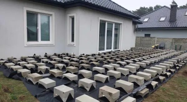 Budowa tarasu z deski kompozytowej na bloczkach betonowych. Podkład z agrowłókniny chroni przed chwastami.