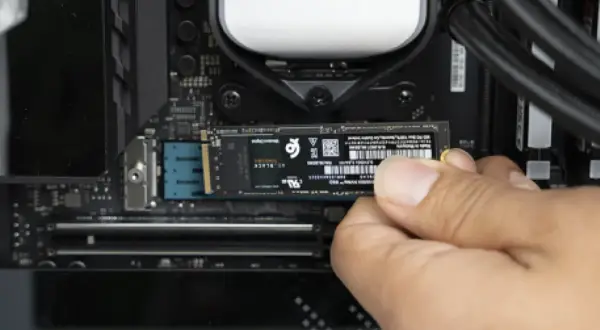 Dłoń instaluje dysk M.2 PCIe na płycie głównej komputera.