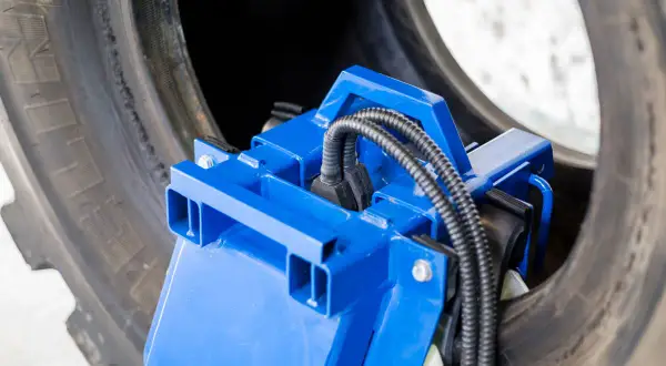 Herramienta azul para manipular el talon neumatico de un neumático grande.