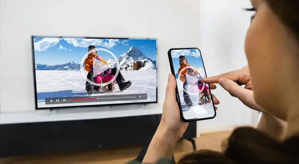 Kobieta przesyła wideo z telefonu na telewizor.