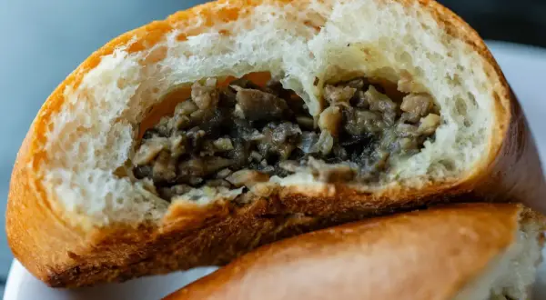 Puszysta bułka z pieczarkami, przekrojona na pół, odsłaniająca aromatyczne, drobno posiekane grzyby. Idealna na szybką przekąskę.