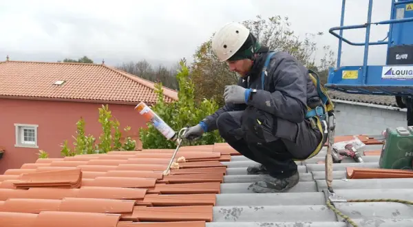 Trabajador aplicando espuma para impermeabilizar tejado de tejas.