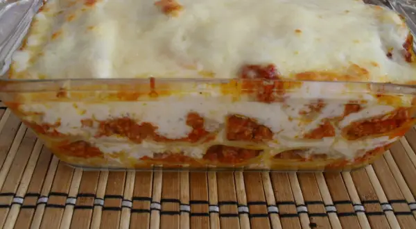Pyszne cannelloni z mięsem mielonym, zapieczone pod warstwą sera i sosu, prezentują się apetycznie w szklanym naczyniu.