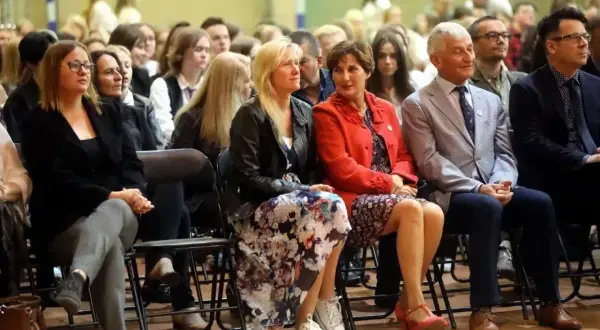 Uczestnicy sali, w tym nauczyciele, siedzą w pierwszym rzędzie, słuchając uważnie. To ważna rada pedagogiczna.